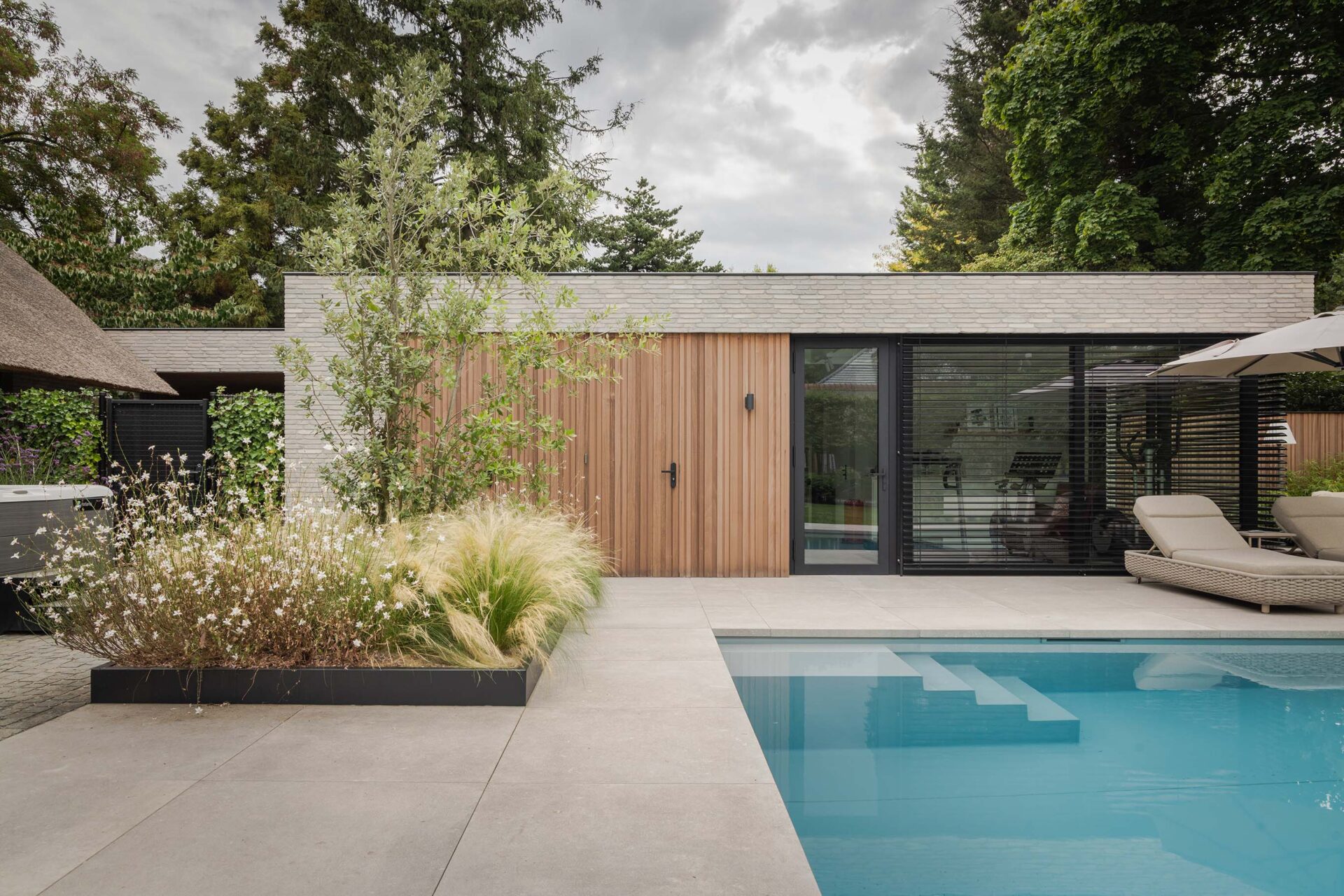 Poolhouse met zwembad en plantvak. 