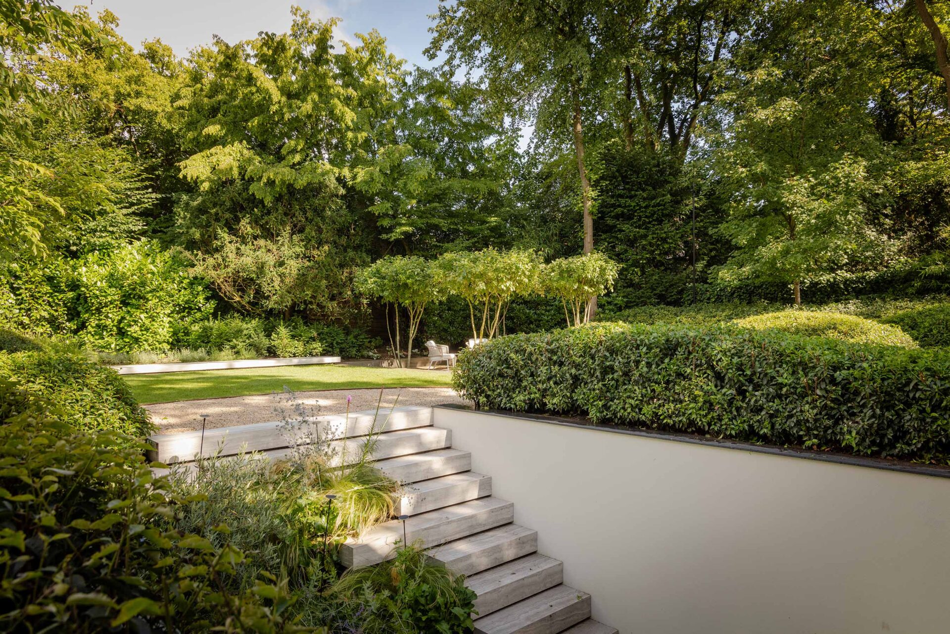 Op maat gemaakte trap van hout welke verschillende trede lengtes heeft in de villatuin. 