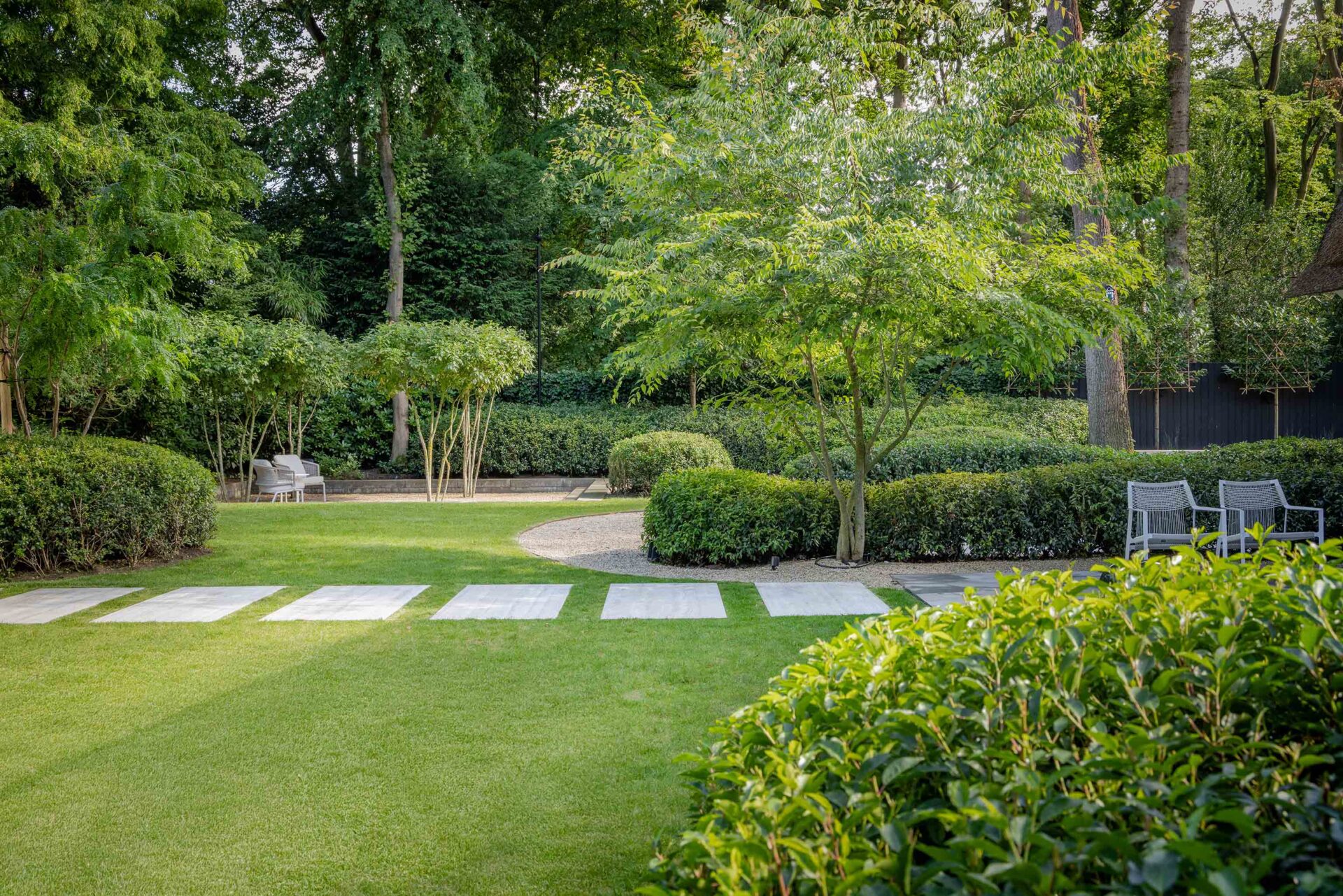 Villatuin met zicht op gazon en grote grijze stapstenen, rechthoekig. 