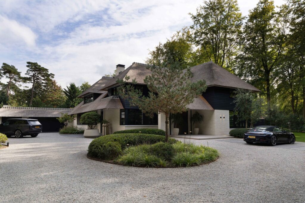 Moderne villa Blaricum met tuin door studio meulenberg zicht op de entree van de villa en rotonde voor het huis met lichtgekleurd grind.