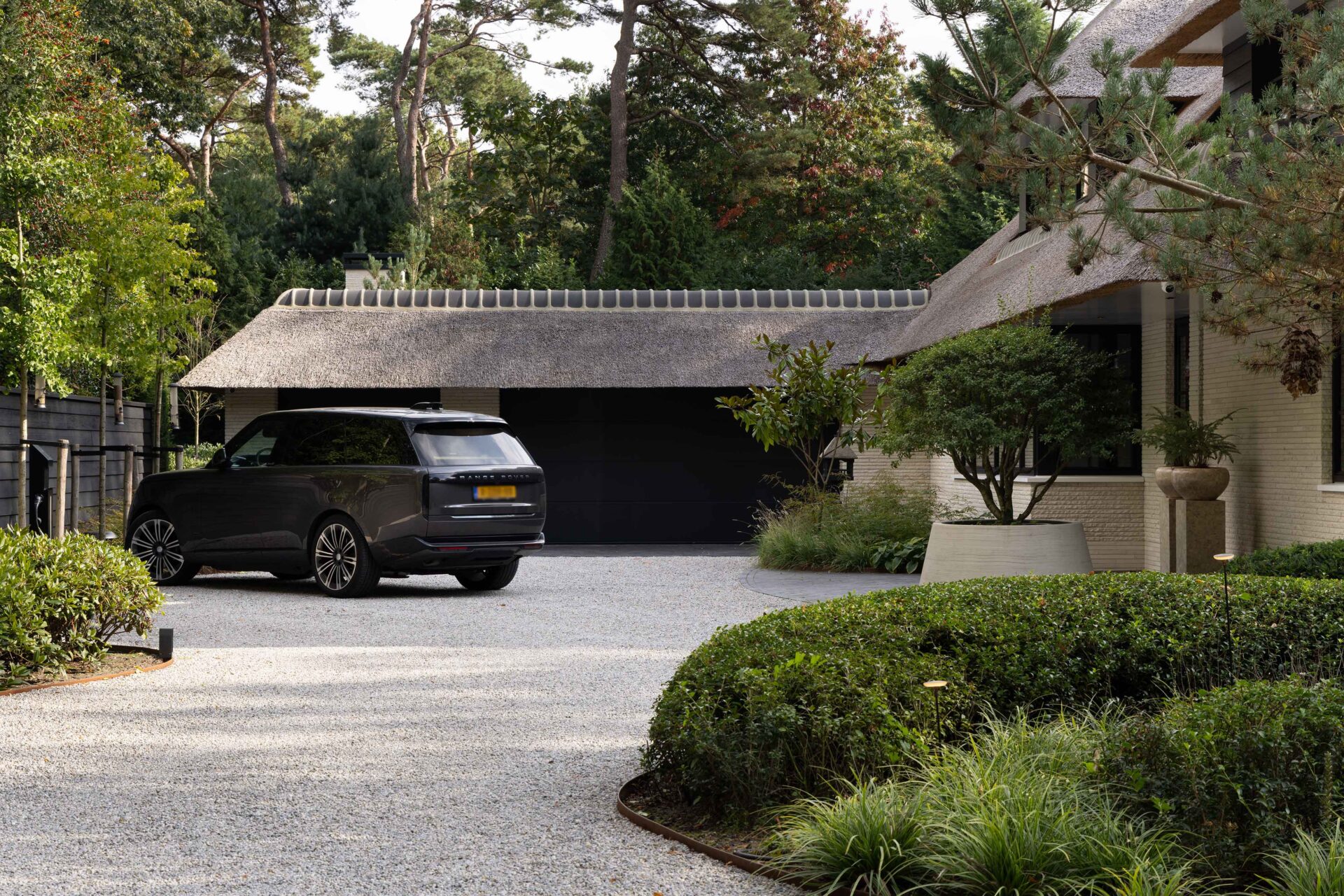 Zicht op grondrotonde aan voorzijde villa met geparkeerde auto. 