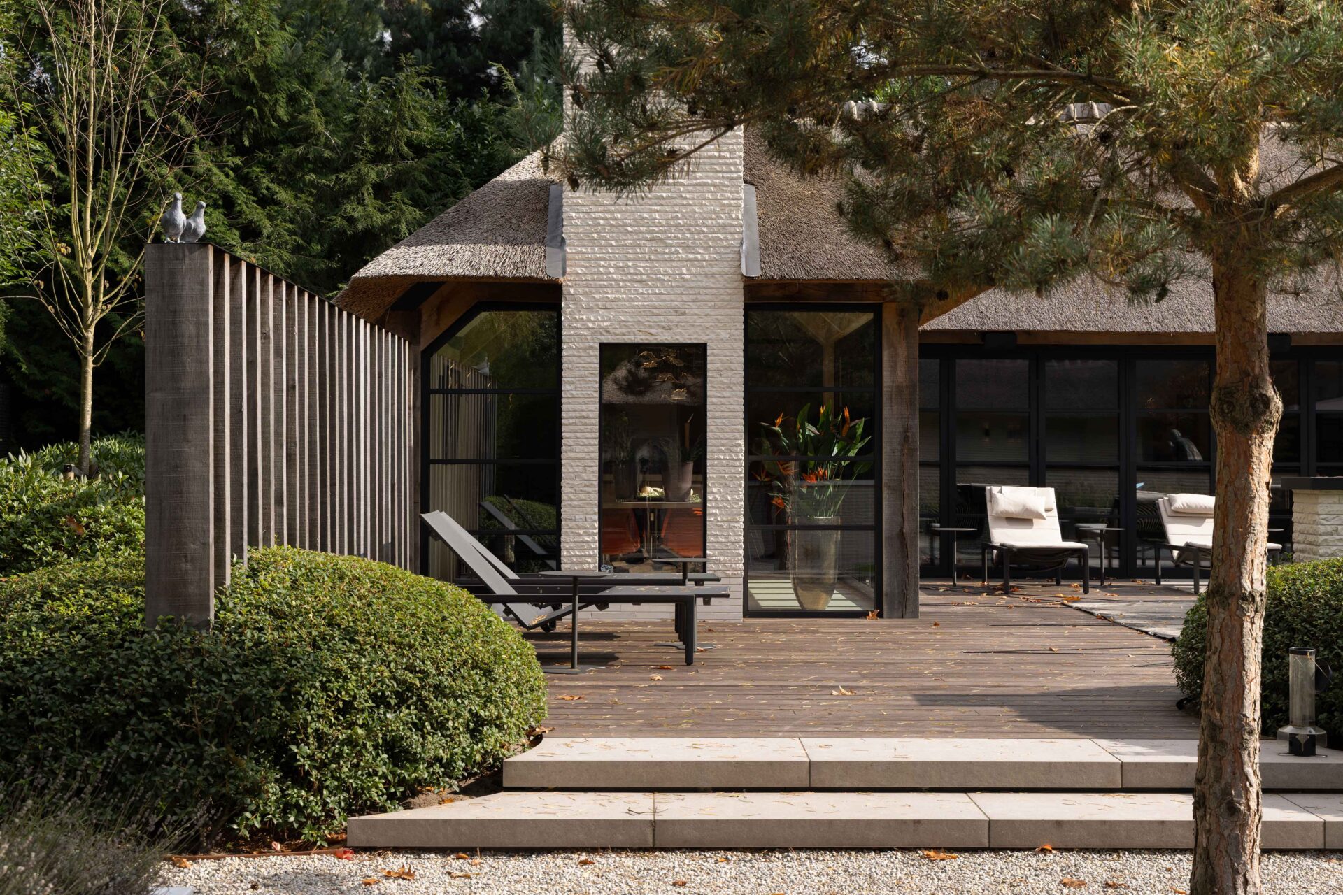 Moderne villa Blaricum met zicht op zwevend elichtgekleurde traptreden naar de vlonder toe en het poolhouse. 