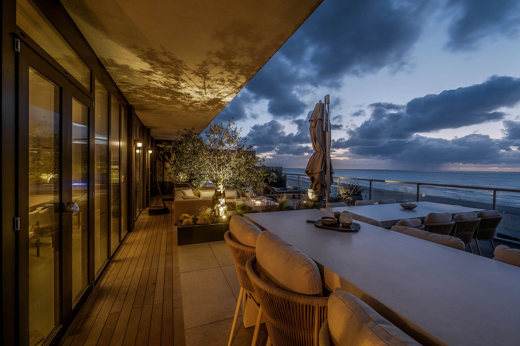 Avondbeeld daktuin Kijkduin met zicht over de eettafel en over de zee. 