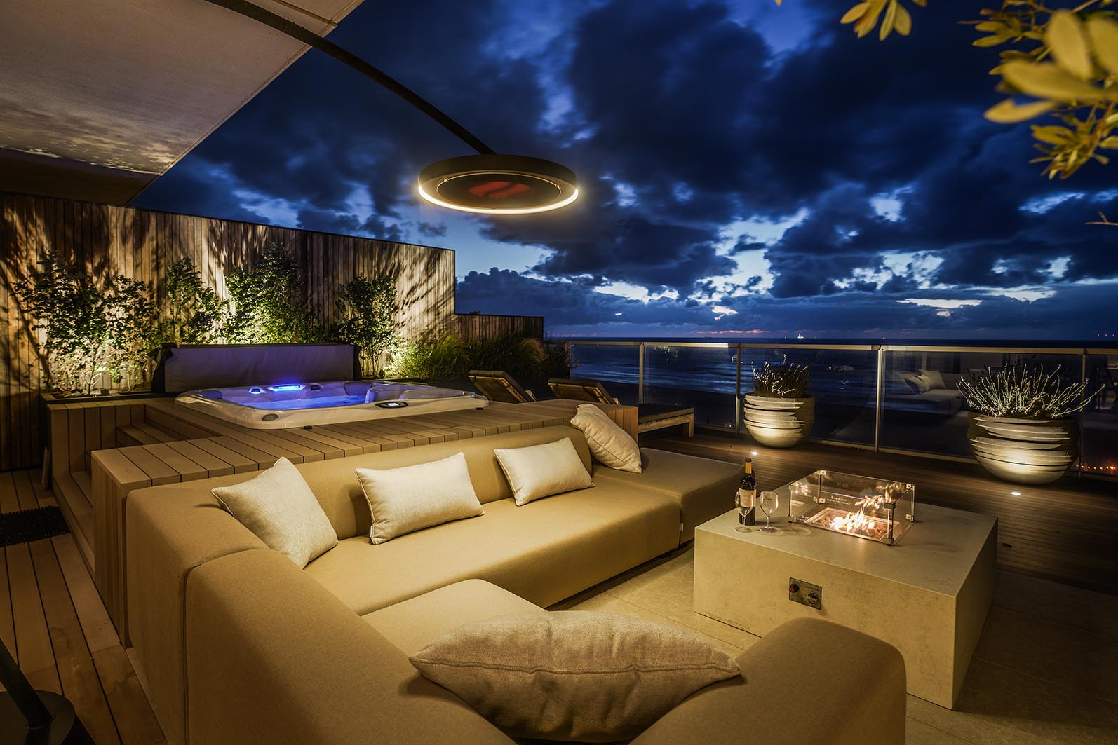 Daktuin Kijkduin in de avond met sfeerverlichting en de luxe loungehoek met uitzicht over zee. 
