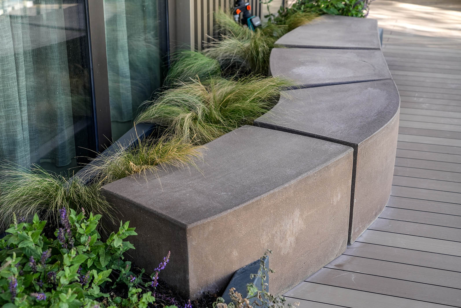 Daktuin Kijkduin met detailbeeld van betonnen zitblokken in glooiende vorm met daarachter beplanting. 