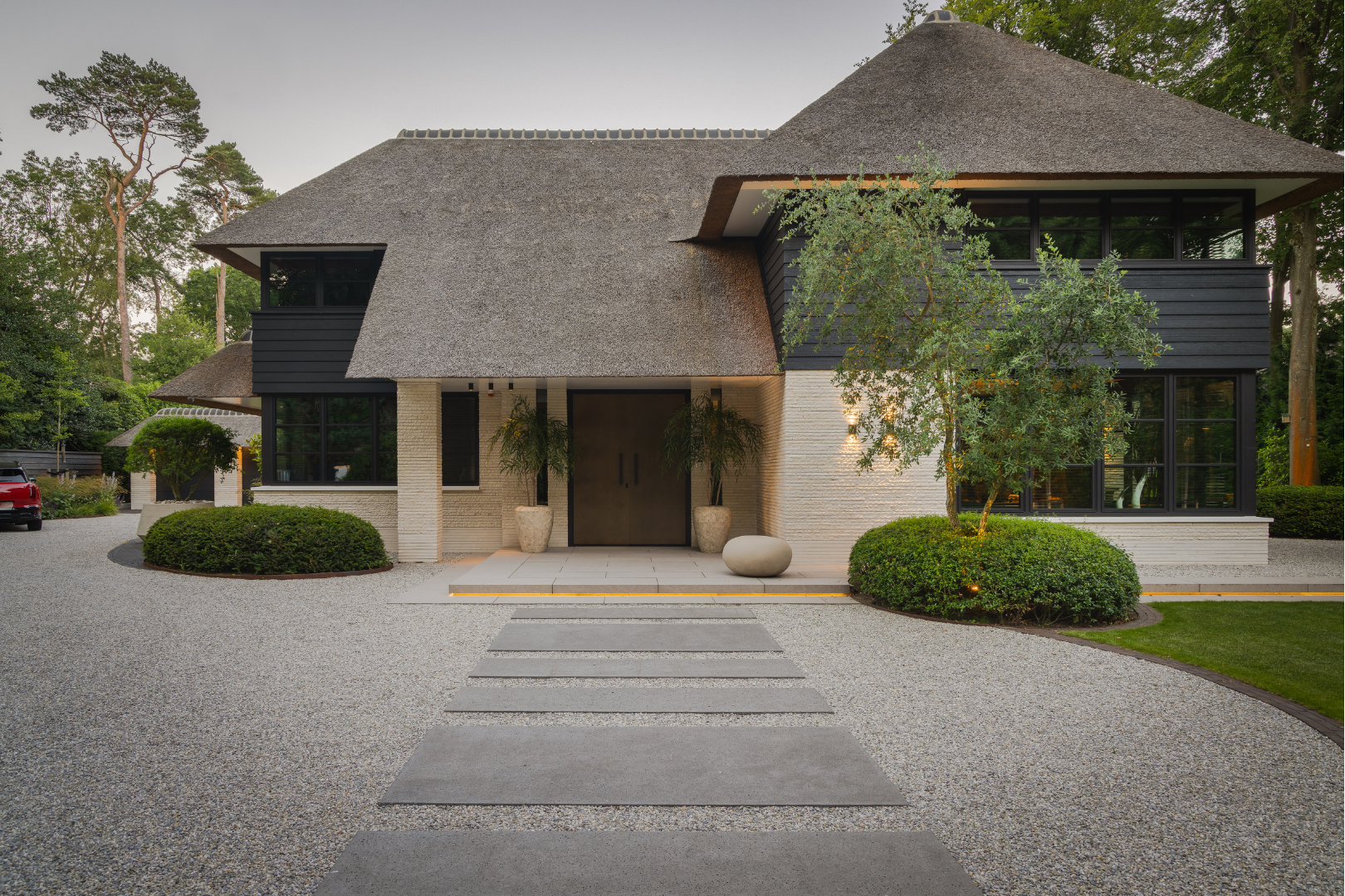 Zicht op zitterras buiten met luxe lounge meubelen direct naast grote raampartij van de villa. 