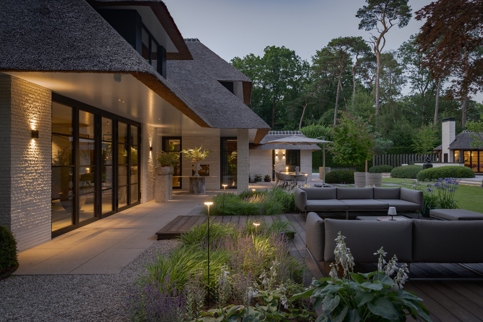 Moderne villa Blaricum met zicht op zwevend elichtgekleurde traptreden naar de vlonder toe en het poolhouse. 